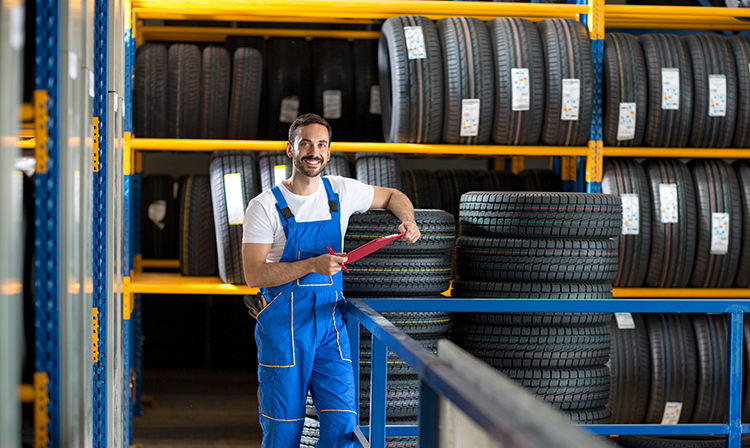 Garage worker with tyre racks and clipboard - Tyre Fitting, Wheel Alignment & Class 4 MOT